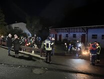 Hier sehen sie mehrere Leute mit Laternen und Fackeln.
