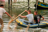 Hier sehen Sie wie 2 Personen in einem Schlauchboot von einer 3. Person beim Anlegen unterstützt werden.